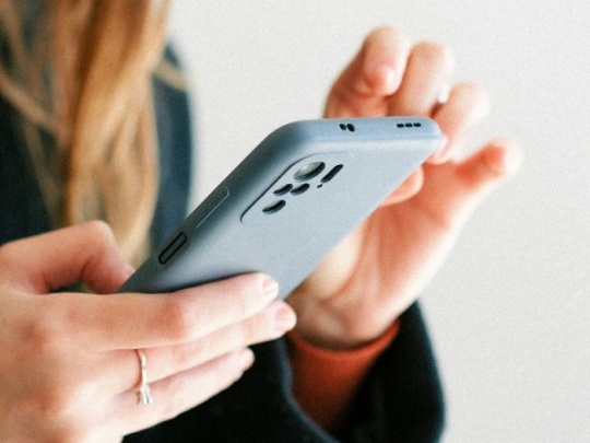 Photographie d'une femme tenant un téléphone portable