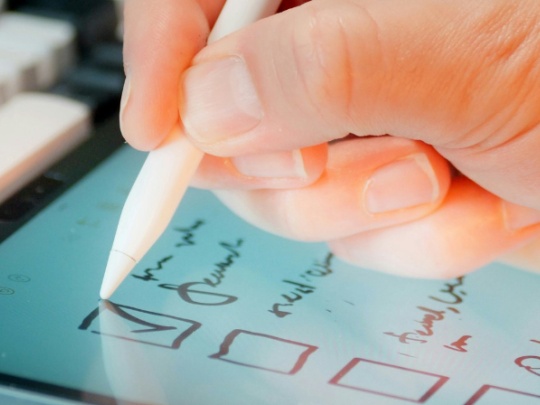 Photographie d'une main écrivant sur une tablette tactile